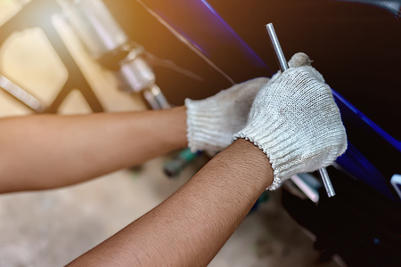 Image is close up. People holding hand are repairing a motorcycle Use a wrench and a screwdriver to work.の写真素材