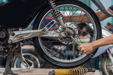 People use hand are repairing a motorcycle Use a wrench to work. Use the wrench to tighten the cylinder.の写真素材