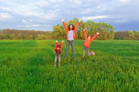 Happy mother with two kids on green fieldの写真素材