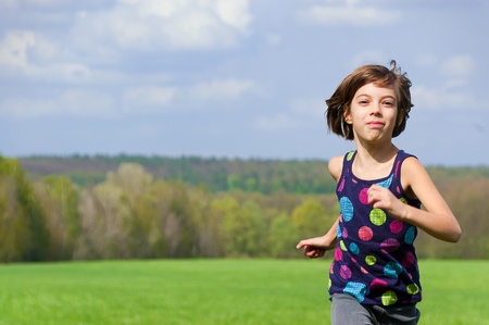 Girl running outdoors on green fieldの写真素材