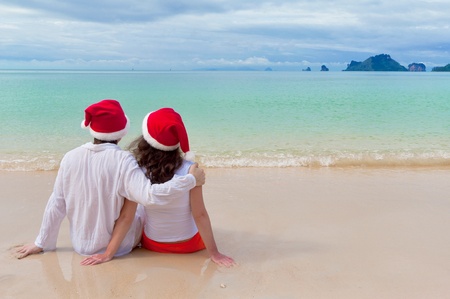 Christmas tropical vacation. Romantic couple in santa hats on beachの写真素材