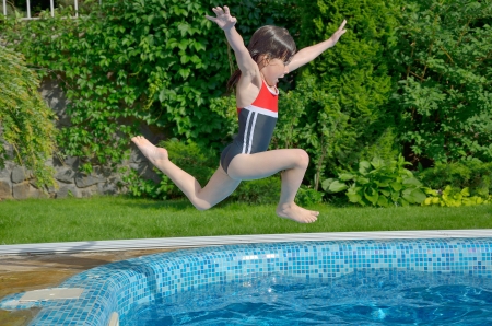 Happy active child jumps to swimming pool  Beautiful smiling girl having fun on summer vacation  Kids sport and holidayの写真素材