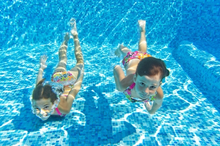 Happy smiling underwater children in swimming pool, beautiful girls swim and having fun  Kids sport on family summer vacation  Active holidayの写真素材