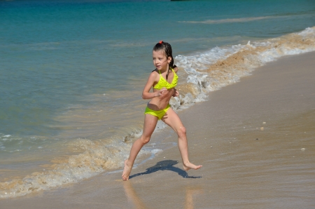 Happy girl plays in sea on tropical beach, child on family vacationの写真素材