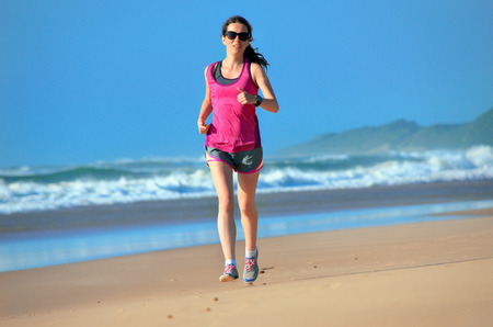 Woman running on beach, beautiful girl runner jogging outdoors, training for marathon, exercising and fitness conceptの写真素材