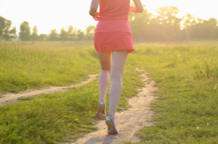 Blurred background: woman runner running on rural road on sunset or sunrise, sport and fitness conceptの写真素材