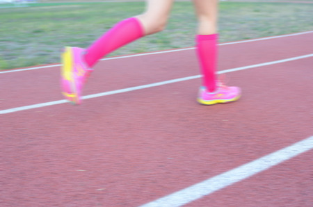 Blurred background: woman runner's legs running on track, sport and fitness conceptの写真素材