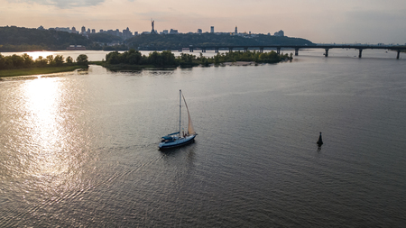Aerial view of Kiev city skyline on sunset, yacht sailing in Dnieper river from above, Kyiv, Ukraineの写真素材