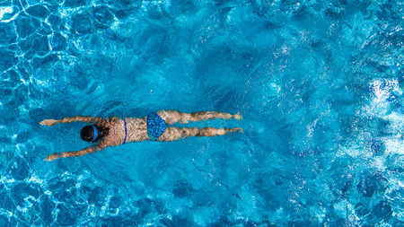Aerial top view of woman in swimming pool water from above, tropical vacation holiday conceptの写真素材