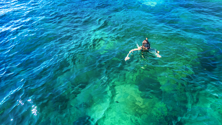 Aerial top view of woman snorkeling from above, girl snorkeler swimming in a clear tropical sea...
