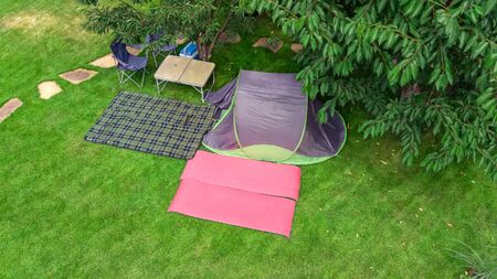 Aerial top view of campsite from above, tent and camping equipment under tree, family vacation in...
