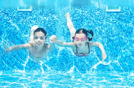 Children swim underwater in swimming pool, happy active girls have fun under water, kids fitness and...