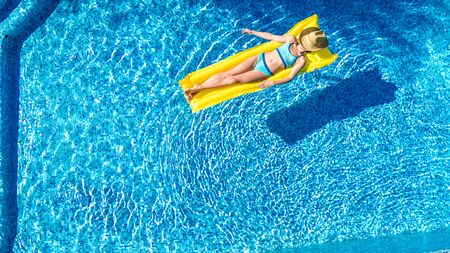 Girl relaxing in swimming pool, child swims on inflatable mattress and has fun in water on family...