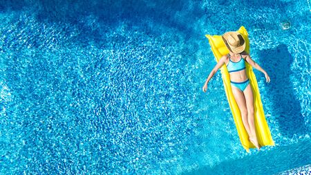 Girl relaxing in swimming pool, child swims on inflatable mattress and has fun in water on family...