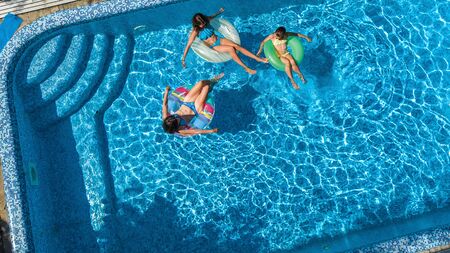 Family in swimming pool aerial drone view from above, happy mother and kids swim on inflatable ring...