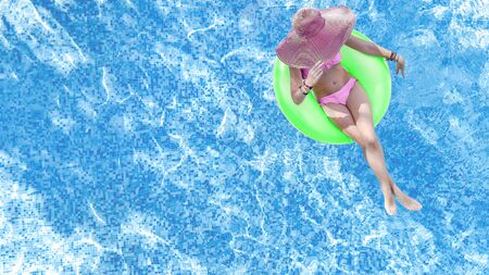 Beautiful woman in hat in swimming pool aerial top view from above, young girl in bikini relaxes and...