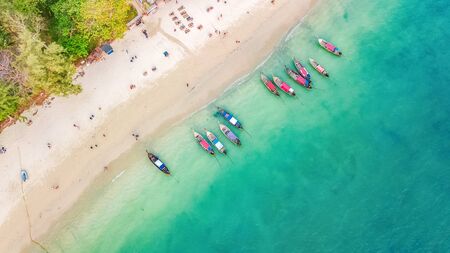 Aerial top view of crystal clear sea water and white beach with longtail boats from above, tropical island or Krabi province in Thailandの写真素材