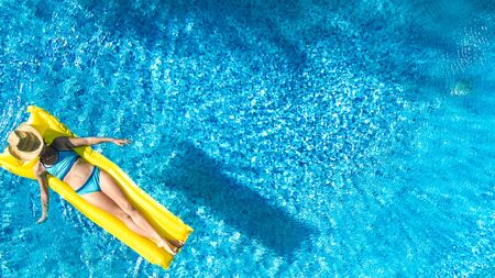 Girl relaxing in swimming pool, child swims on inflatable mattress and has fun in water on family...