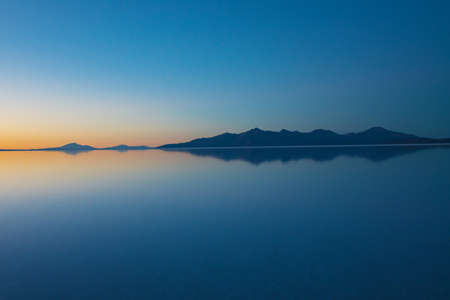 Sunrise on Salar de Uyuni in Bolivia covered with water, salt flat desert and sky reflectionsの写真素材