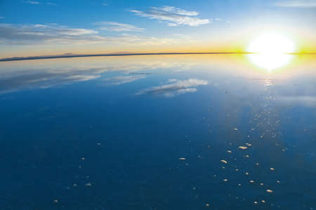 Sunrise on Salar de Uyuni in Bolivia covered with water, salt flat desert and sky reflectionsの写真素材