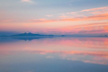 Sunrise on Salar de Uyuni in Bolivia covered with water, salt flat desert and sky reflectionsの写真素材