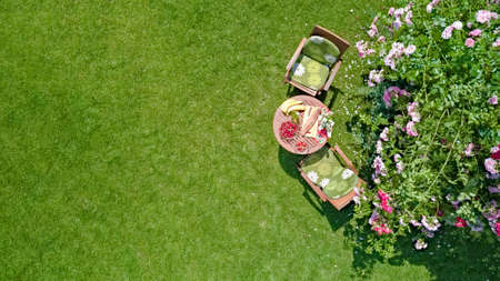 Decorated table with bread, strawberry and fruits in beautiful summer rose garden, aerial top view of romantic date table food setting for two from aboveの写真素材