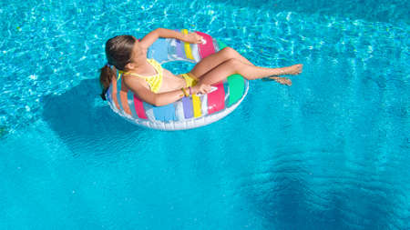 Active young girl in swimming pool aerial top view from above, child relaxes and swims on inflatable...