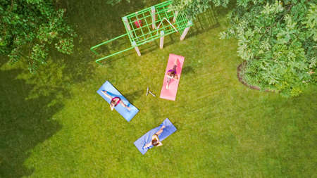Family fitness and sport outdoors, group of active girls doing workout in park, aerial top view from...