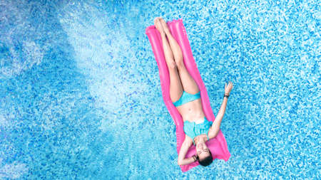 Beautiful young woman in swimming pool aerial top view from above, young girl in bikini relaxes and...