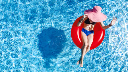 Beautiful woman in hat in swimming pool aerial top view from above, young girl in bikini relaxes and...