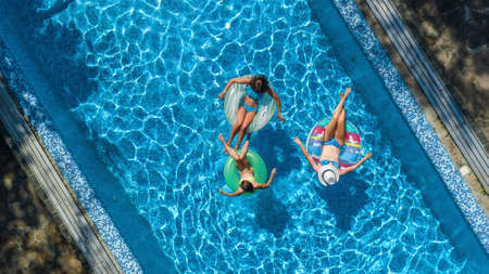 Family in swimming pool aerial drone view from above, happy mother and kids swim on inflatable ring...