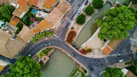Aerial top view of boats and lock in Canal du Midi, road and bridge from above, Southern France