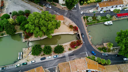 Aerial top view of boats and lock in Canal du Midi, road and bridge from above, Southern France