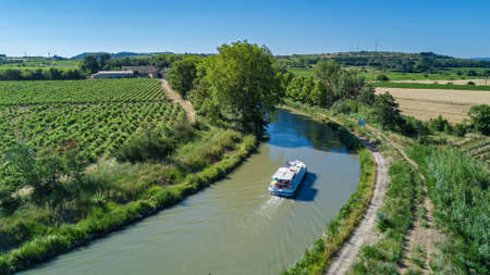 Aerial top view of boat in Canal du Midi from above, family travel by barge and vacation in Southern Franceのeditorial素材