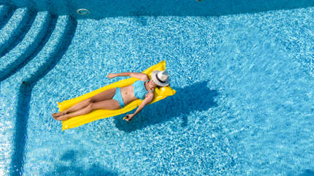 Beautiful young girl relaxing in swimming pool, woman swims on inflatable mattress and has fun in...