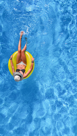 Beautiful woman in hat in swimming pool aerial view from above, young girl relaxes and has fun on...