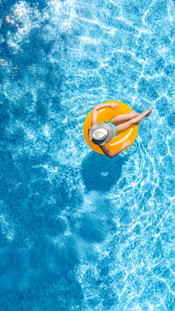 Active young girl in swimming pool aerial top view from above, child relaxes and swims on inflatable...