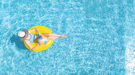 Active young girl in swimming pool aerial top view from above, child relaxes and swims on inflatable ring donut and has fun in water, family vacation, tropical holiday resortの写真素材