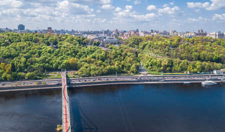Kyiv city skyline and Dnipro river aerial drone view from above, Kiev hills, pedestrian Park bridge...
