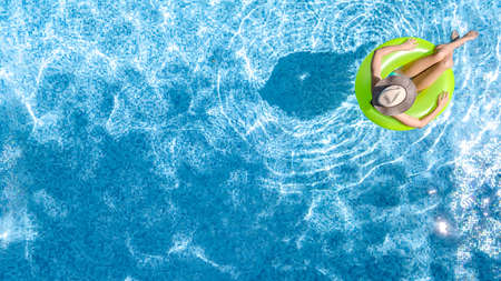 Active young girl in swimming pool aerial top view from above, teenager relaxes and swims on...