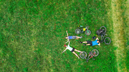 Family cycling on bikes aerial drone view from above, happy active parents with child have fun and...