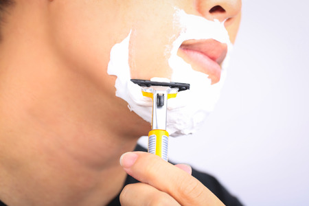 Close up young man shaving his face.の写真素材