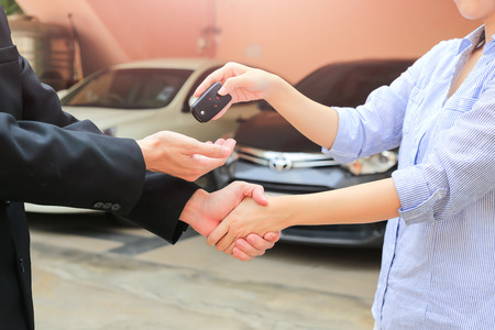 Business hand giving a key of buyer at rental car.の写真素材