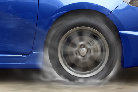 Blue car racing spinning wheel burns rubber on floor.の写真素材