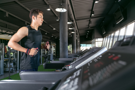 Smart man running on treadmill in gym.