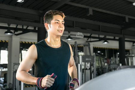 Smart man running on treadmill in gym.の写真素材