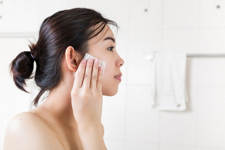 Beautiful woman removing makeup from her face in bathroom.の写真素材