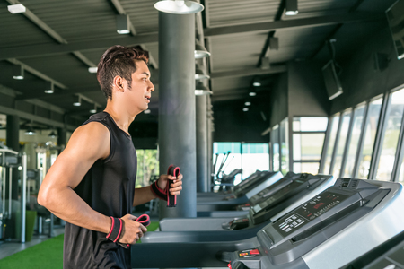 Smart man running on treadmill in gym.の写真素材