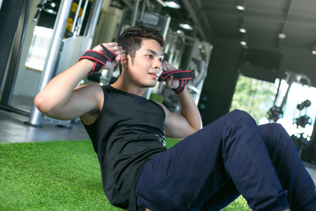 Asian sport man working out his abs in a gym.の写真素材