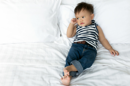 Baby boy thinking on white bed. copy space.の写真素材